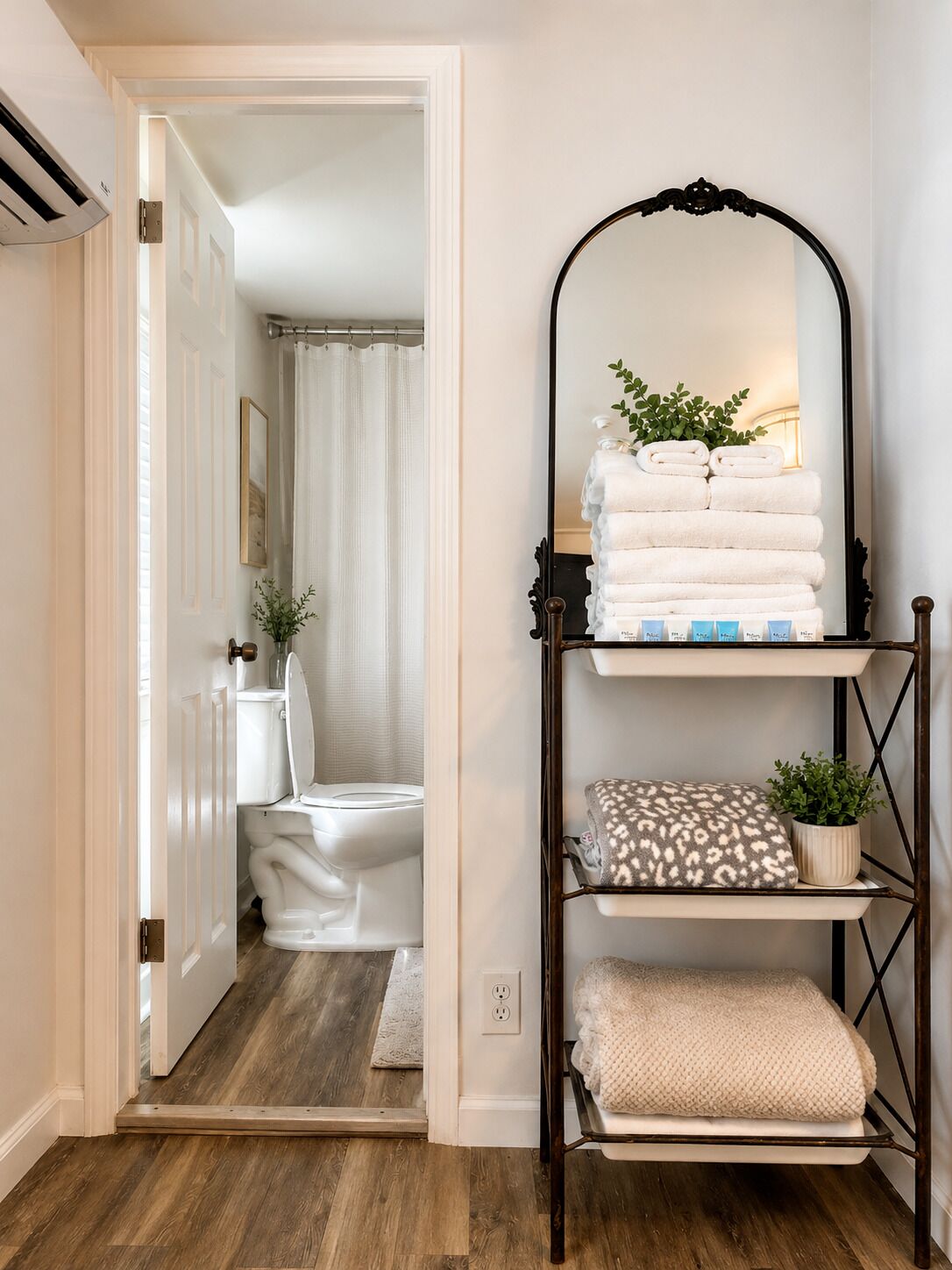 Une salle de bain avec des toilettes blanches, un rideau de douche et un porte-serviettes avec des serviettes pliées.