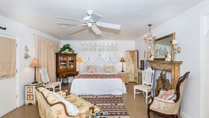 A bedroom with a bed, a ceiling fan, a fireplace, and a mirror. - Couples Getaway - 1 block to downtown- Jacuzzi tub! (Fredericksburg)