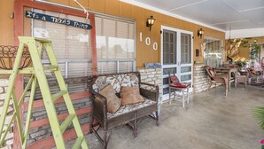 A covered outdoor area with a wicker sofa, a wooden chair, and a green ladder. - Couples Getaway - 1 block to downtown- Jacuzzi tub! (Fredericksburg)