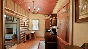 Una cocina acogedora con paredes de madera, una zona de comedor con mesa y sillas, y una chimenea.