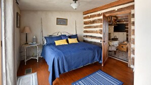 Ein Schlafzimmer mit Holzboden, einem Bett mit blauer Bettwäsche, einer weißen Lampe und einem Bild an der Wand.