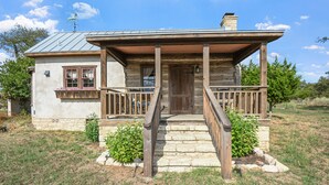 Ein rustikales Blockhaus mit einer Holzveranda, Steintreppen und einem Metalldach.