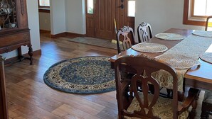 Uma sala de jantar com uma mesa de madeira, cadeiras e um tapete estampado.