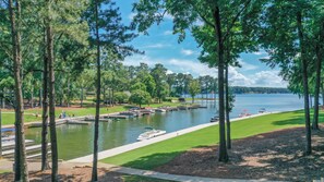 A lakeside view with docked boats, a grassy area, and trees. - Lakefront Getaway "Right There" on the water in Reynolds community 2 bed/2 bath  (Greensboro)