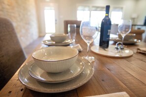 A dining table with a bowl and wine glasses, a bottle, and a chair. - Private Hot Tub - Newly renovated - Short Drive to downtown (Fredericksburg)