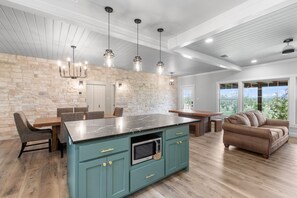 A modern kitchen with a large island, stone wall, and pendant lighting. - Private Hot Tub - Newly renovated - Short Drive to downtown (Fredericksburg)