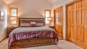 Ein Schlafzimmer mit einem hölzernen Bett, zwei Nachttischlampen, einem großen Fenster und einem Holzschrank.