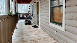 A wooden porch with a covered area, a wooden bench, and a door.