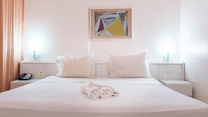 A neatly made bed with white linens, two pillows, and a rolled towel in a hotel room. - Rede Andrade LG Inn Recife (Recife)