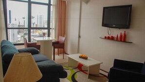 A modern living room with a sofa, coffee table, and TV. - Rede Andrade LG Inn Recife (Recife)