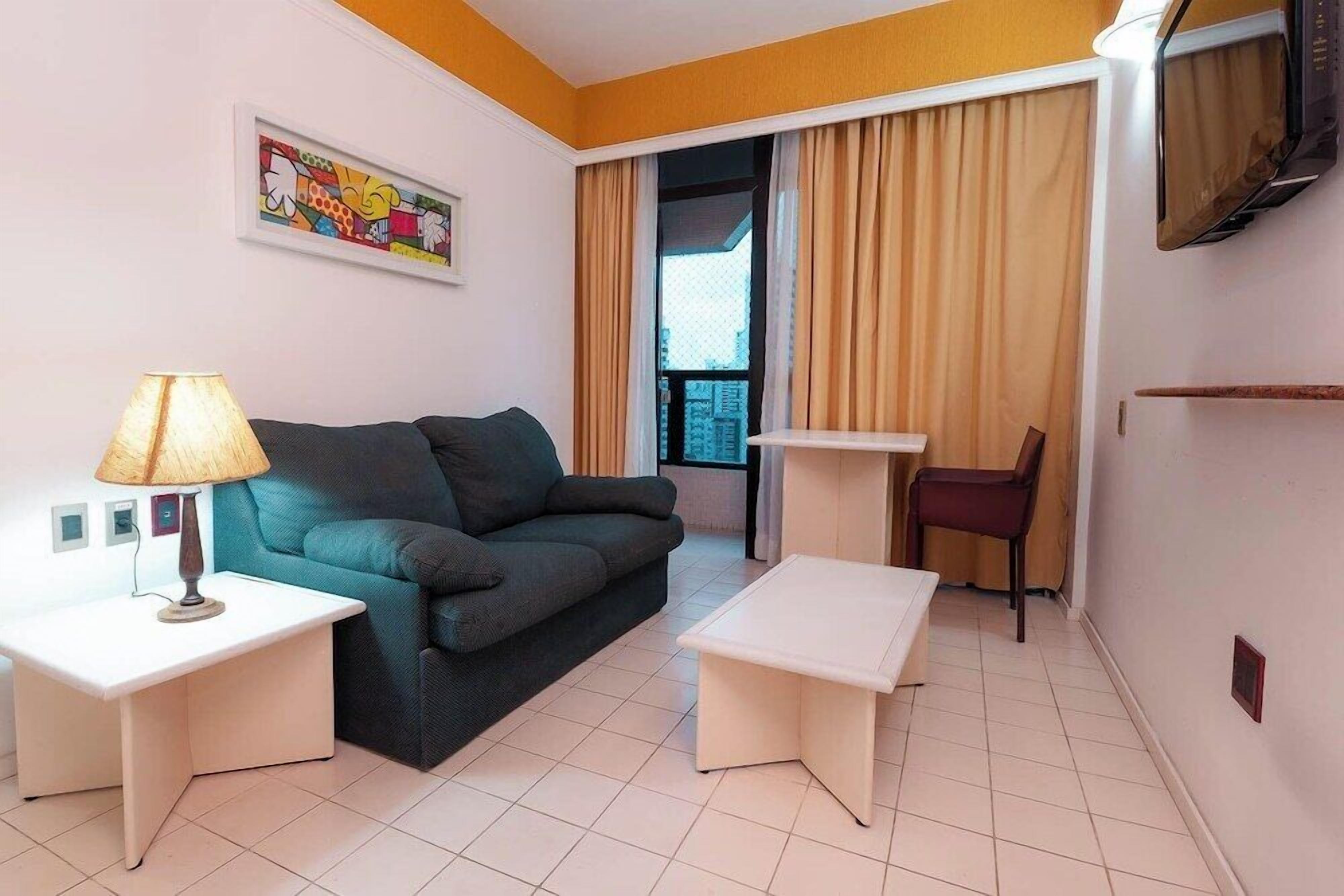 A modern living room with a sofa, two side tables, a chair, and a television.