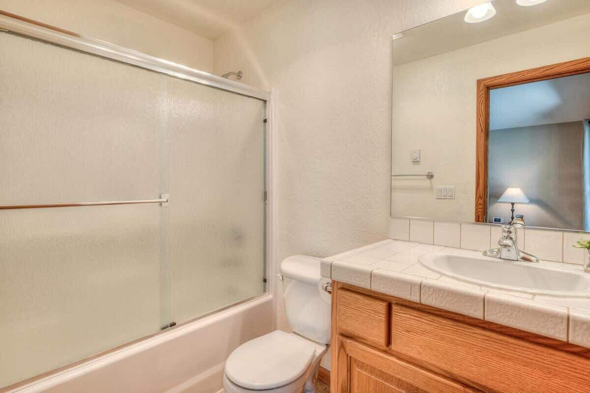Une salle de bain avec une douche à parois de verre, des toilettes, un lavabo avec un miroir et des meubles en bois.