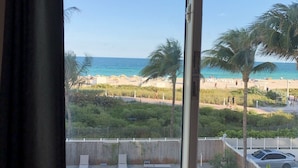 A pool with lounge chairs, a view of the beach, and a clear sky. - South Beach Ocean View King Bed + Free Beach Service (Miami Beach)