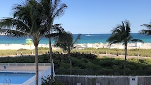A pool area with lounge chairs, a pool, and a view of the beach. - South Beach Ocean View King Bed + Free Beach Service (Miami Beach)