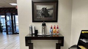 A reception desk with a framed picture, a coffee maker, and condiments. - Budget Inn Laramie (Laramie)