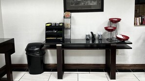A modern room with a black table, a trash bin, a framed picture, and a red bowl stand. - Budget Inn Laramie (Laramie)