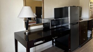 A compact kitchen with a dark countertop, a microwave, a refrigerator, and a lamp. - Budget Inn Laramie (Laramie)