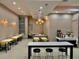 Interior de restaurante con diversas opciones de asientos, incluyendo mesas y cabinas, una zona de bar con taburetes e iluminación colgante.