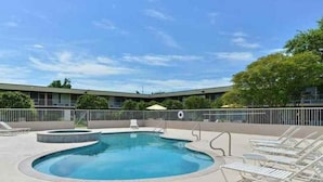 A swimming pool with lounge chairs and a building in the background. - Heritage Inn & Suites by Capital O Baton Rouge I 10 (Baton Rouge)