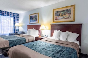 A hotel room with two beds, a desk, and a chair. There are two framed pictures on the wall. - Heritage Inn & Suites by Capital O Baton Rouge I 10 (Baton Rouge)