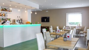A modern restaurant with a bar area, white chairs, and a flat-screen TV on the wall. - hotel villa fernanda  (Massa Lubrense)