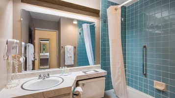 A bathroom with a sink, mirror, and shower.