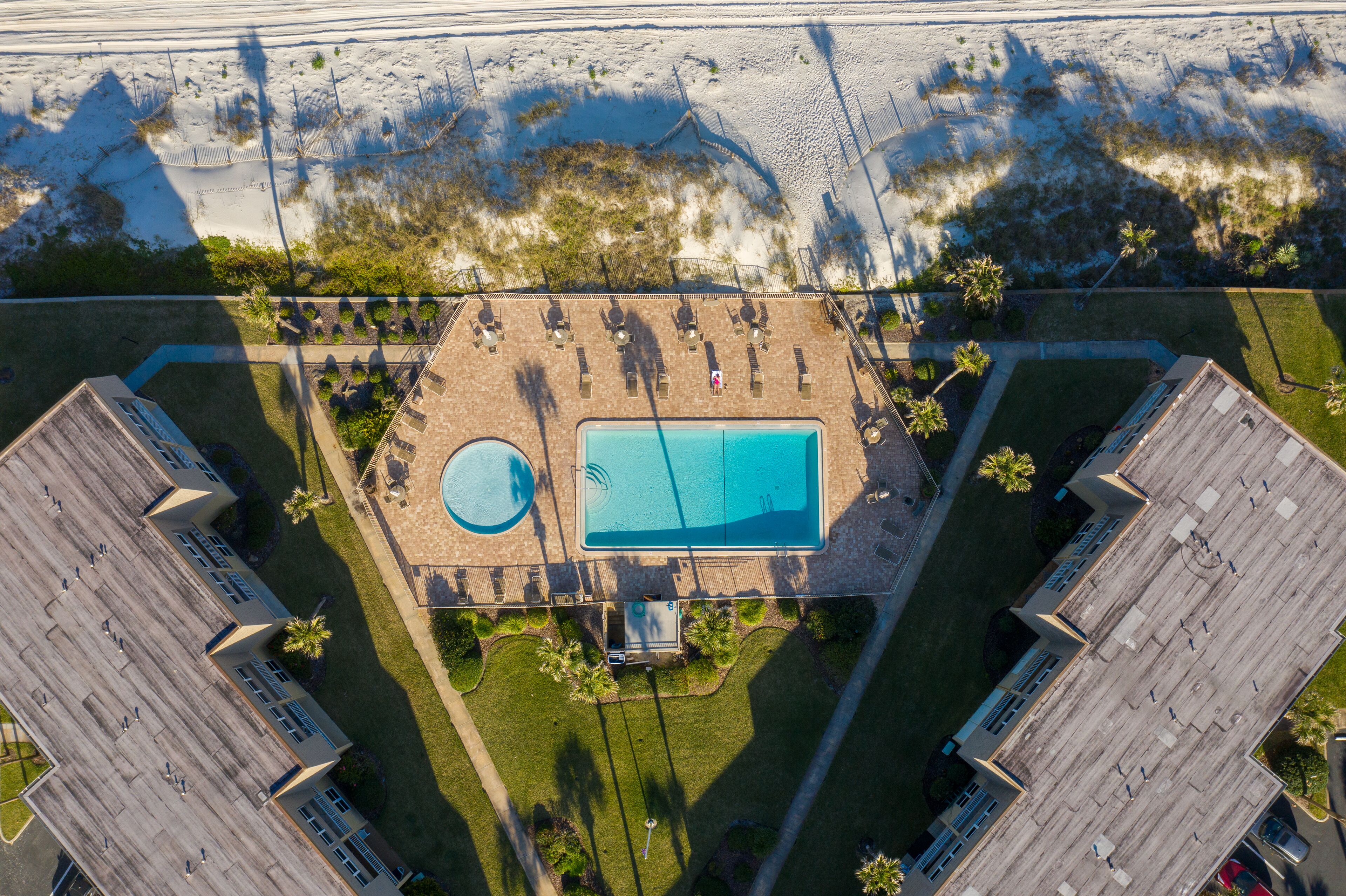 Vista aérea de un complejo turístico con piscina, zona de descanso y acceso a la playa.