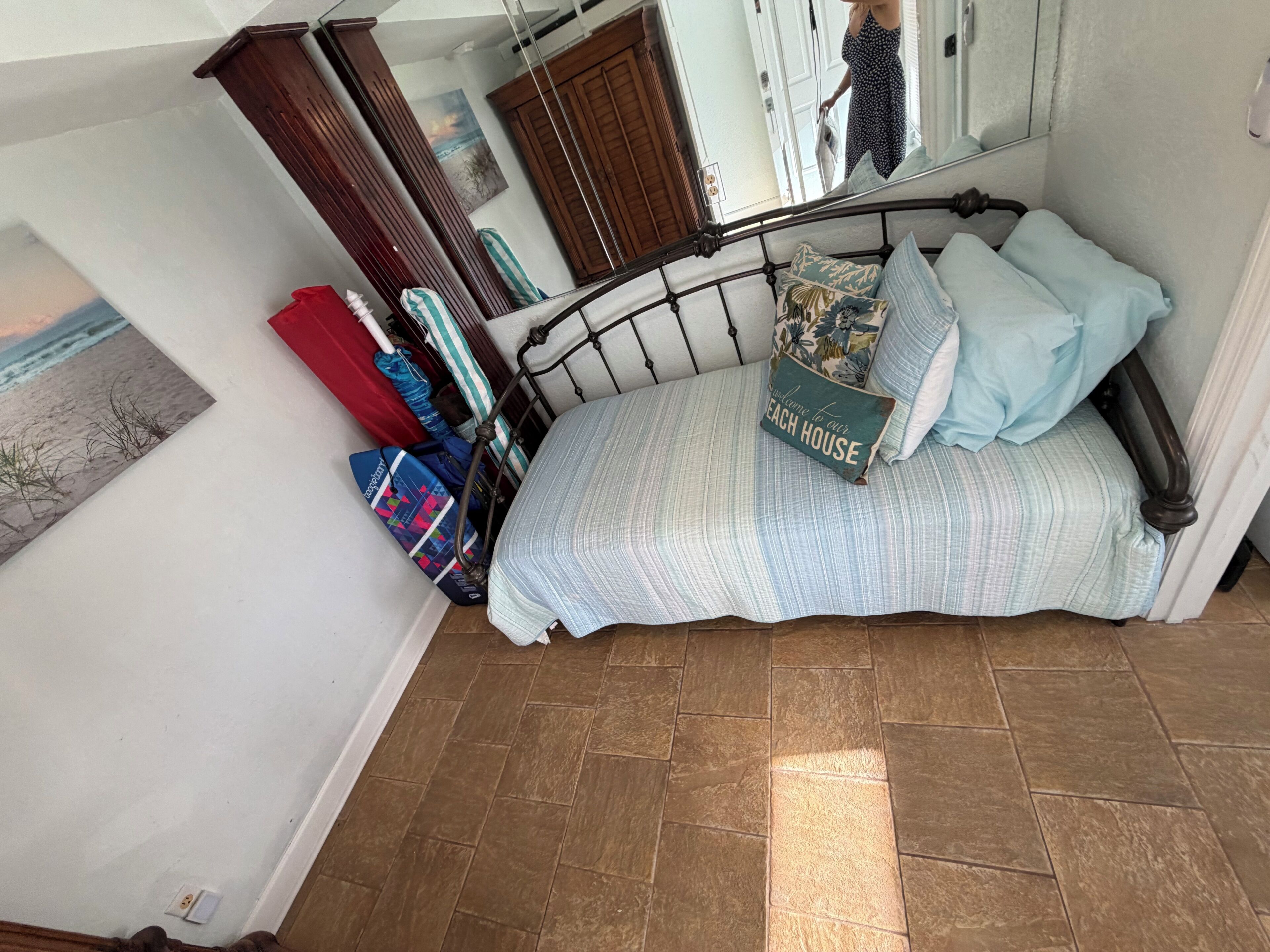 Un dormitorio con una cama, un espejo, una puerta y una pared con un cuadro.