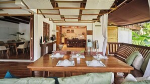 A dining area with a wooden table set for four, surrounded by green upholstered sofas. - The Strand Boutique Resort (Boracay Island)
