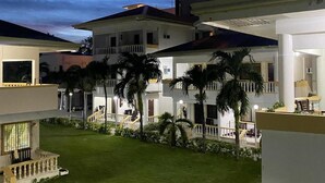 Un patio con césped, palmeras y un edificio con balcones.