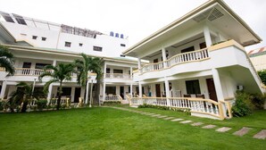 A multi-story hotel with a central courtyard, balconies, and a well-maintained lawn. - Bans Beach Resort (Boracay Island)