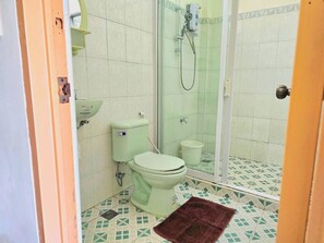 A bathroom with a toilet, a shower enclosure, and a small rug on the floor. - Bans Beach Resort (Boracay Island)