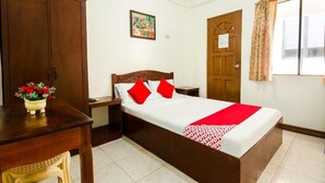 A bedroom with a wooden bed, a nightstand, a desk with a vase of flowers, and a wardrobe. - Bans Beach Resort (Boracay Island)
