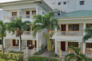 A multi-story hotel with balconies, palm trees, and a green roof. - Bans Beach Resort (Boracay Island)