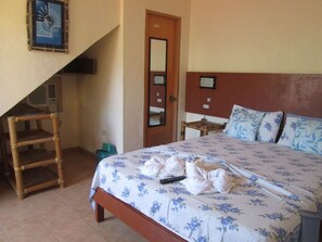 A hotel room with a bed, a wooden chair, a small table, and a mirror on the wall. - Sulu Plaza Beach Hotel (Boracay Island)