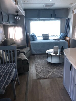 Cozy retreat with a comfortable bed, compact table, and plush chair.