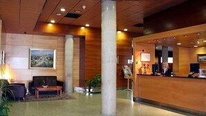A hotel lobby with a reception desk, a sofa, a coffee machine, and a painting on the wall. - Eco Via Lusitana (Madrid)
