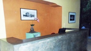 Un espace d’accueil comprenant un comptoir de réception, un vase de fleurs et deux tableaux encadrés accrochés au mur.