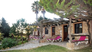 A stone building with a covered patio, outdoor seating, and a garden with various plants. - Quinta do Mar da Luz Aldeamento (Lagos)