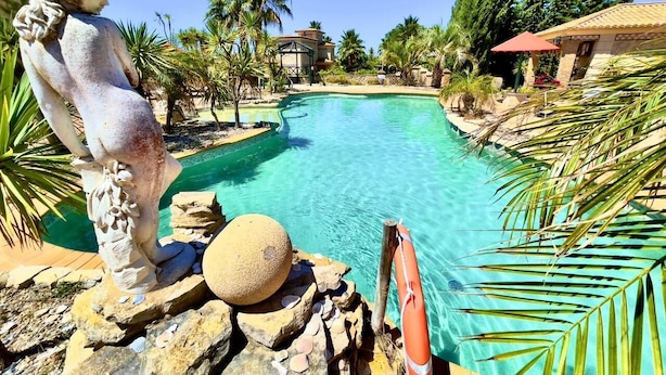 A clear swimming pool with a statue, palm trees, and a gazebo in the background. - Quinta do Mar da Luz Aldeamento (Lagos)