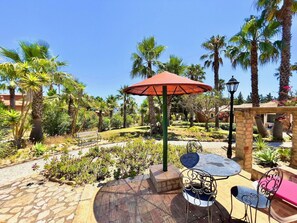 An outdoor patio area with stone flooring, a red umbrella, and metal chairs. - Quinta do Mar da Luz Aldeamento (Lagos)
