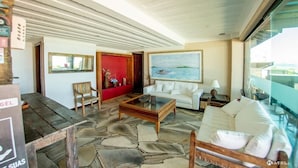 A modern hotel lobby with a white sofa, a wooden coffee table, and a large painting of a landscape. - Pier Beach Hotel (Cabo Frio)