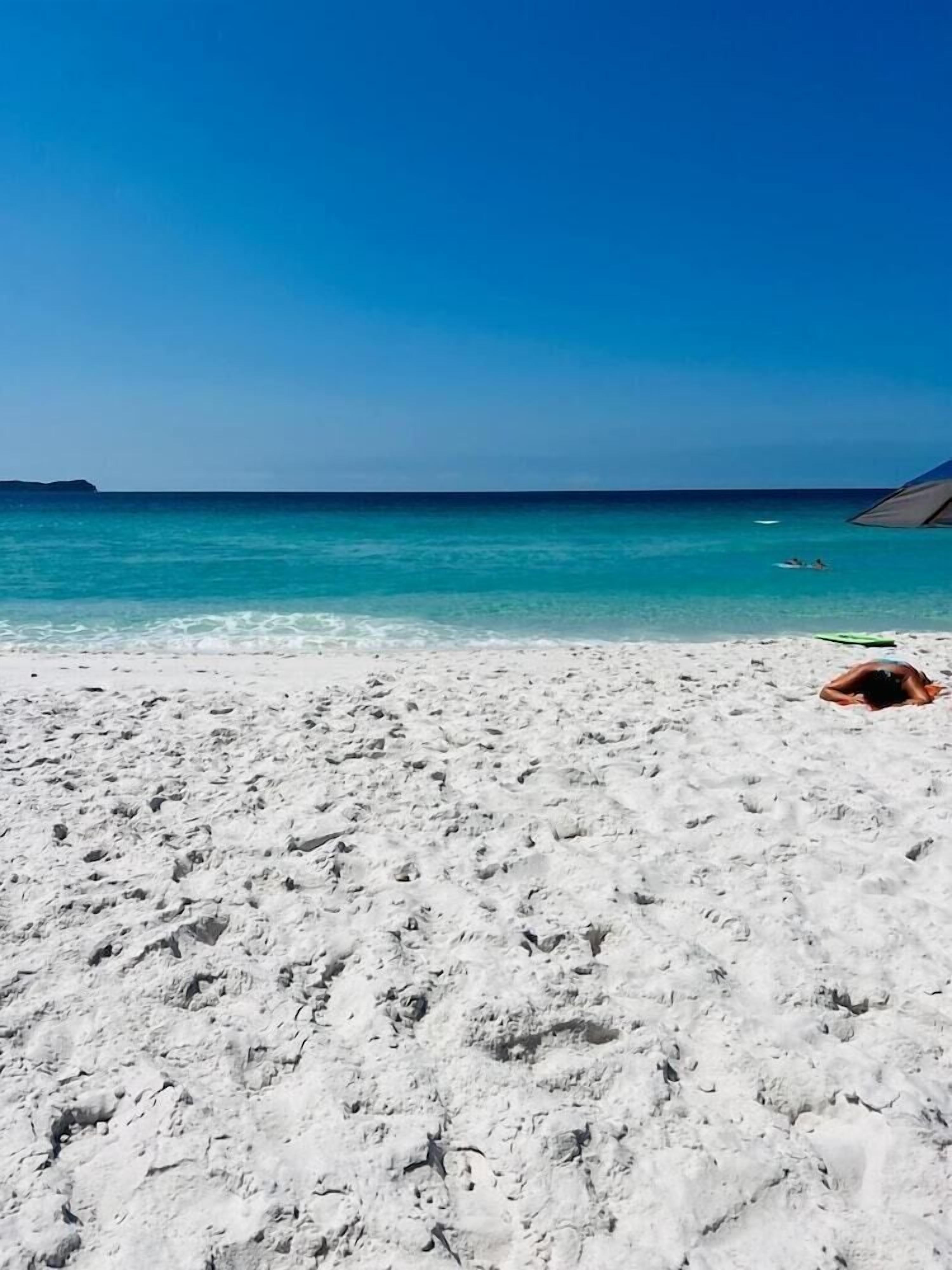 A beach with white sand and clear turquoise water.