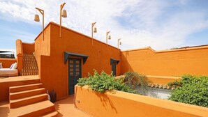Edifici amb teulada plana, escales i una petita zona de jardí amb plantes.