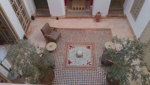 Un pati amb un paviment de pissos, una font al centre, un sofà i plantes en testos.