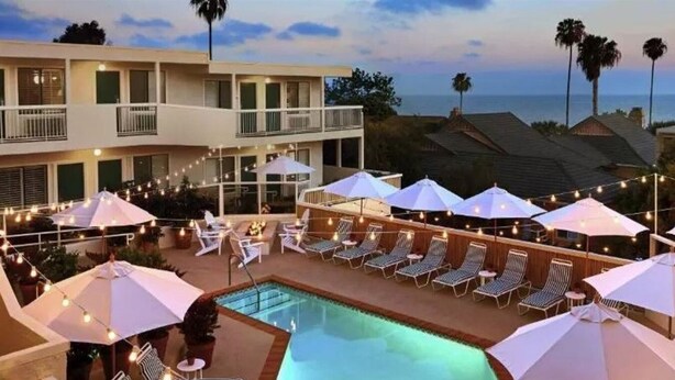 A poolside area with lounge chairs and umbrellas, overlooking a residential neighborhood and the ocean. - Laguna Beach House (Laguna Beach)