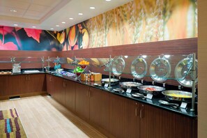 A buffet area with multiple food stations, a patterned wall, and wooden cabinets. - Fairfield Inn Suites By Marriott Paramus (Paramus)