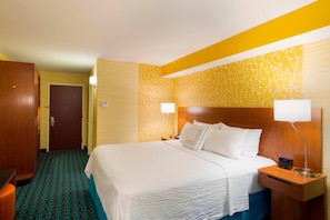 A hotel room with a bed, bedside tables, a nightstand, a lamp, and a door. - Fairfield Inn Suites By Marriott Paramus (Paramus)
