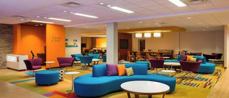 A modern lounge area with sofas, chairs, and a reception desk.