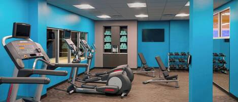 Un gimnasio con cintas de correr, elípticas y bancos de pesas.